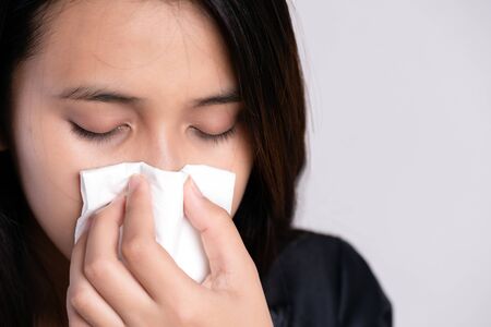 Close up young asian woman got sick, flu and nose allergy sneezing in a tissue. Healthcare and Coronavirus concept.の写真素材