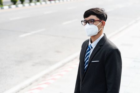 Close up of a businessman in a suit wearing Protective face mask and cough, get ready for Coronavirus and pm 2.5 fighting against in city background.の写真素材