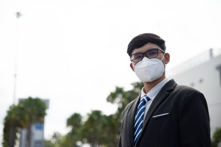 Close up of a businessman in a suit wearing Protective face mask and cough, get ready for Coronavirus and pm 2.5 fighting against in city background.の写真素材
