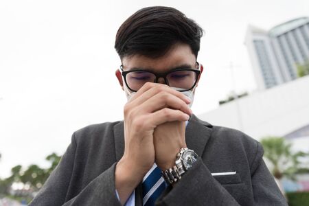 Close up of a businessman in a suit wearing Protective face mask and cough, get ready for Coronavirus and pm 2.5 fighting against in city background.の写真素材