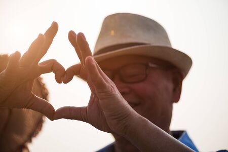 A happy senior couple asian old man and woman showing heart sign, love symbol, happy marriage. Senior healthcare and relationship concept.の写真素材