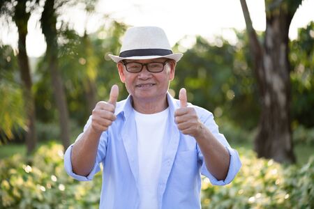 A happy old man with thumbs up smiling and laughing in the garden, happy marriage. Senior healthcare concept.の写真素材
