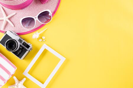 Beach accessories picture frame, sunglasses, starfish, beach hat and sea shell on yellow pastel background for summer holiday and vacation concept.の写真素材