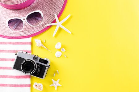Summer holiday, travel and vacation concept. Retro film camera, sunglasses, starfish, beach hat and sea shell on yellow background, Flat lay with copy space.の写真素材