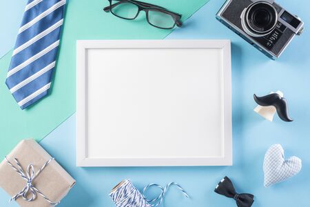 Happy Fathers Day background concept with picture frame, retro camera, decorated bowtie, necktie, eyeglasses, gift box and mustache on bright pastel background.の写真素材