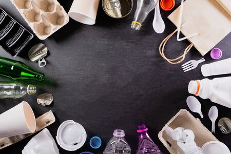 Top view of Different garbage materials with recycling symbol on black background. Recycle, World...