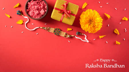 Raksha Bandhan, Indian festival with beautiful Rakhi and  Rice Grains on red background.  A traditional Indian wrist band which is a symbol of love between Sisters and Brothers.の写真素材