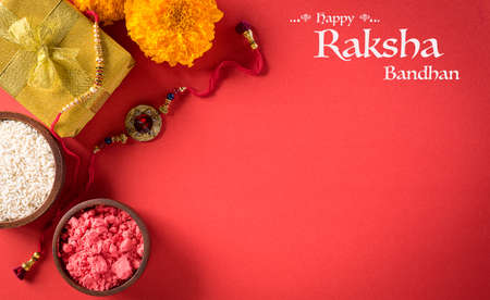 Raksha Bandhan, Indian festival with beautiful Rakhi and  Rice Grains on red background.  A traditional Indian wrist band which is a symbol of love between Sisters and Brothers.の写真素材