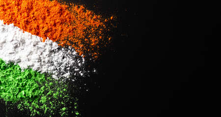 Indian Independence Day celebration background concept. Symbolic flag colors, red, green and orange powders colour splashed over dark background.の写真素材