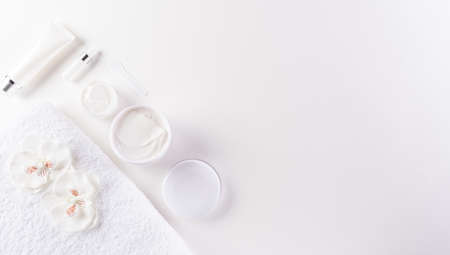 Cosmetic bottle containers, skin cream with flowers. Natural beauty and spa concept, Top view on white table background.の写真素材