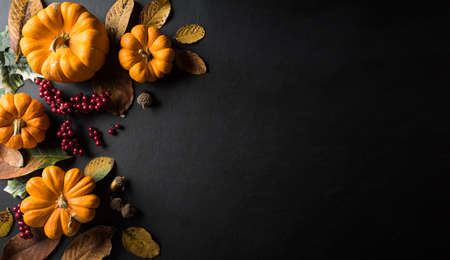 Autumn background decor from dry leaves and pumpkin on blackboard background. Flat lay, top view with copy space for Autumn, fall, Thanksgiving concept.の写真素材
