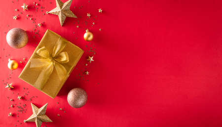 Christmas background decoration concept. Top view of golden gift box with christmas ball and star on red background.の写真素材
