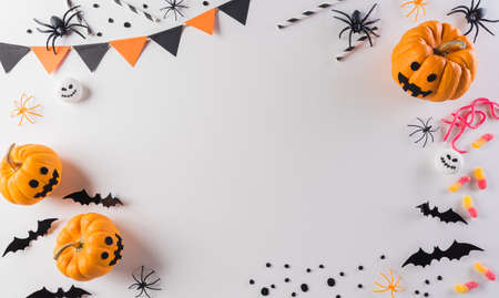 Halloween decorations made from pumpkin, paper bats and black spider on pastel orange background. Flat lay, top view with copy space for text.の写真素材