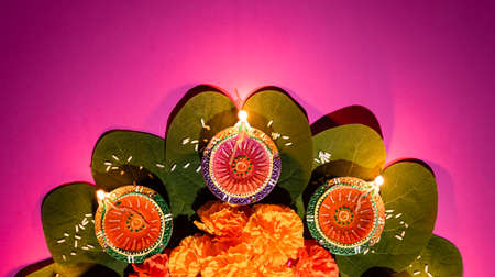 Happy Dussehra. Clay Diya lamps lit during Dussehra with yellow flowers, green leaf and rice....