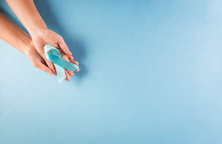 World diabetes day awareness concept. Hand holding blue ribbon, symbolic bow color raising awareness in diabetes day on pastel background,  14 November.の写真素材