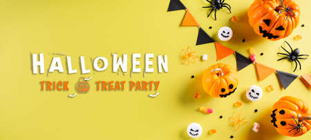Top view of Halloween crafts, orange pumpkin, ghost, bat and black spider on pastel yellow background. Flat lay, top view with Halloween text.の写真素材