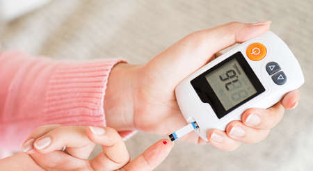 World diabetes day concept. Close up hands holding lancing device with blood to checking blood sugar...