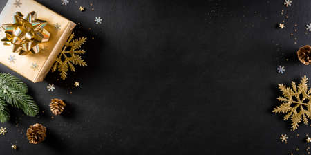 Christmas and new year background concept. Top view of Christmas gift box, spruce branches, pine cones and snowflake on black wooden background.の写真素材