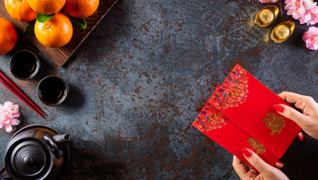 Chinese new year decorations, pow or red packet, orange and gold ingots on dark stone background. Chinese characters FU in the article refer to fortune good luck, wealth, money flow.の写真素材