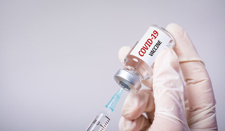 Doctor hand holding syringe and COVID-19 vaccine. Healthcare And Medical concept.の写真素材
