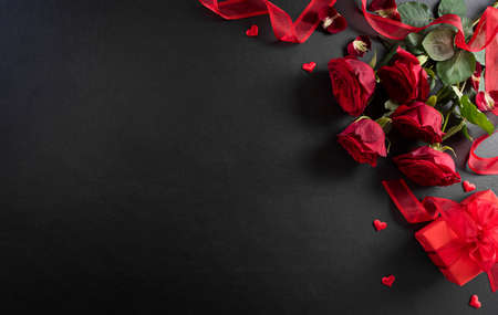 Love and Valentine's day concept made from red rose and gift box on black wooden background. Top view with copy space, flat lay.の写真素材