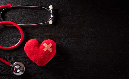 Top view of red heart with doctor physician's stethoscope on dark stone background. Hospital life insurance concept,  World health day concept.の写真素材