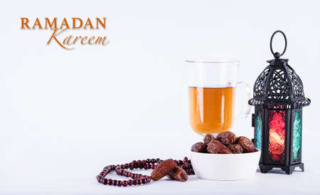 Ramadan food and drinks concept. Ramadan arabian lamp, wood rosary, tea, and dates fruit on white background.の写真素材