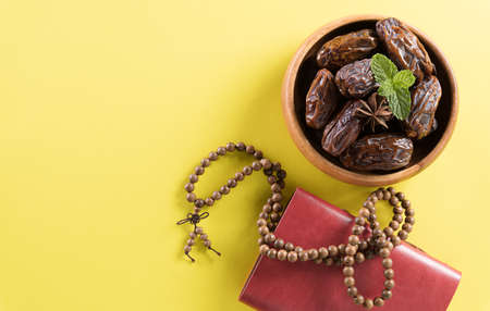 Table top view image of decoration Ramadan Kareem,  dates fruit, aladdin lamp and rosary beads on yellow  background. Flat lay with copy space.の写真素材