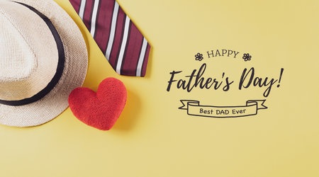 Happy Father's Day inscription with colorful tie, red heart and hat on pastel yellow background.の写真素材