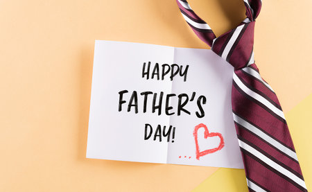 Happy Father's Day inscription in celebrated card and plaid tie on pastel backgroundの写真素材