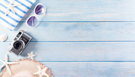 Summer holiday, travel and vacation concept. Sunglasses, starfish, retro camera and seashell on pastel blue wooden background.の写真素材