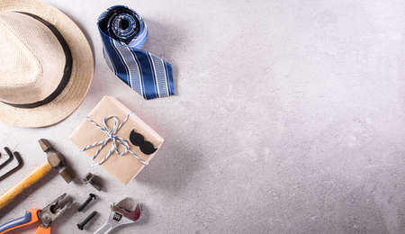 Happy Father's Day decoration with beautiful tie with mustache, hand tools, glasses, gift box and hat on dark stone background.の写真素材
