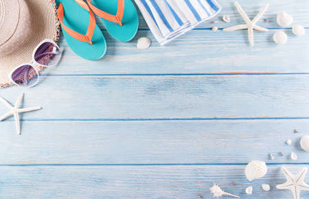 Summer holiday, travel and vacation concept. Sunglasses, starfish, beach hat, flip flop and sea shell on pastel blue wooden background.の写真素材