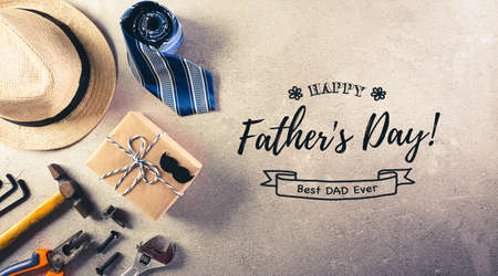 Happy Father's Day decoration with beautiful tie with mustache, hand tools, glasses, gift box and hat with the text on dark stone background.の写真素材