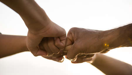 Close up bottom view of people giving fist bump showing unity and teamwork. Friendship happiness...