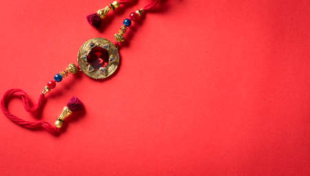 Raksha Bandhan, Indian festival with beautiful Rakhi and  Rice Grains on red background.  A traditional Indian wrist band which is a symbol of love between Sisters and Brothers.の写真素材