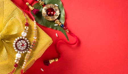 Raksha Bandhan, Indian festival with beautiful Rakhi and  Rice Grains on red background.  A traditional Indian wrist band which is a symbol of love between Sisters and Brothers.の写真素材