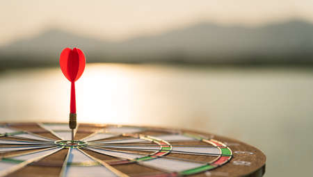 Soft focus shot red darts arrows in the target center on dark sky background. Business target or goal success and winner concept.の写真素材