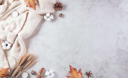 Autumn composition. A cup of coffee, cotton flowers, autumn leaves and sweater on stone background. Flat lay, top view with copy space.の写真素材