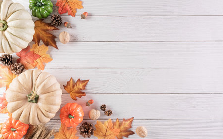 Autumn composition. Pumpkin, autumn or maple leaves and nuts on white wooden background. Flat lay, top view with copy space.の写真素材