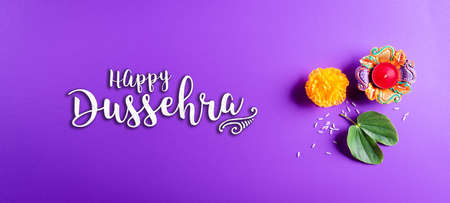 Happy Dussehra. Yellow flowers, green leaf and rice on purple pastel background. Dussehra Indian Festival concept.の写真素材
