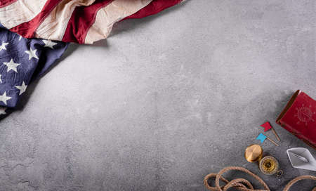 Happy Columbus Day concept. Vintage American flag, compass, paper boat, rope on dark stone background.  Flat lay, top view with copy space.の写真素材