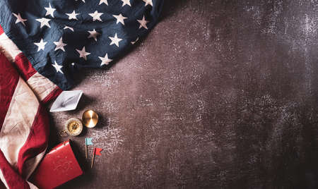 Happy Columbus Day concept. Vintage American flag, compass, paper boat, rope on dark stone background.  Flat lay, top view with copy space.の写真素材