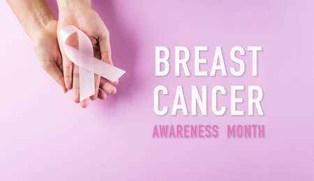 Hands holding pink ribbons, Breast cancer awareness, symbolic bow color raising awareness on women's breast tumor. Healthcare, medicine and breast cancer awareness concept.の写真素材