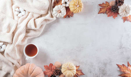Autumn composition. A cup of coffee, cotton flowers, autumn leaves and sweater on stone background. Flat lay, top view with copy space.の写真素材