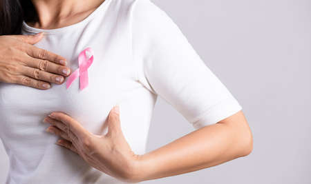 Closeup of pink badge ribbon on woman chest to support breast cancer cause. Healthcare, medicine and breast cancer awareness concept.の写真素材