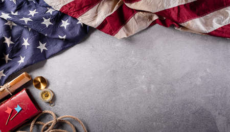 Happy Columbus Day concept. Vintage American flag, compass, paper boat, rope on dark stone background.  Flat lay, top view with copy space.の写真素材