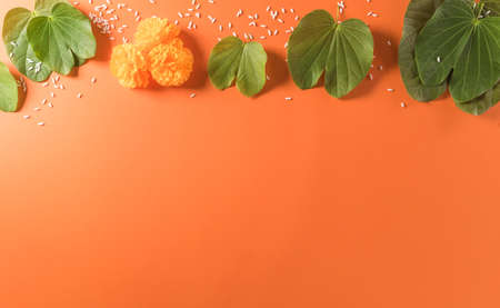 Happy Dussehra. Yellow flowers, green leaf and rice on orange background. Dussehra Indian Festival concept.の写真素材