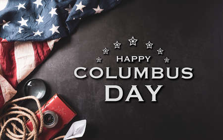 Happy Columbus Day concept. Vintage American flag, compass, paper boat, rope with the text on dark stone background.  Flat lay, top view with copy space.の写真素材