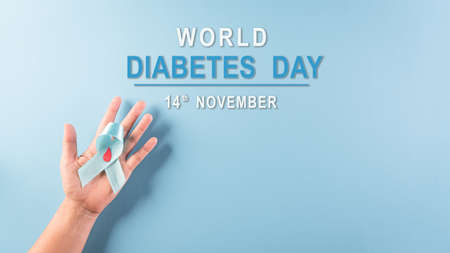 World diabetes day awareness concept. Hand holding blue ribbon, symbolic bow color raising awareness in diabetes day on pastel background,  14 November.の写真素材
